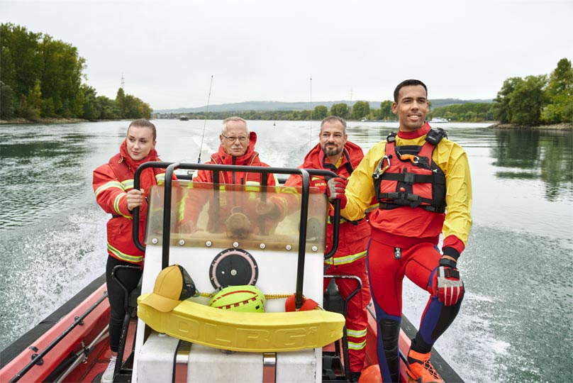 Vier Personen in einheitlicher Ausrüstung auf einem fahrenden Boot